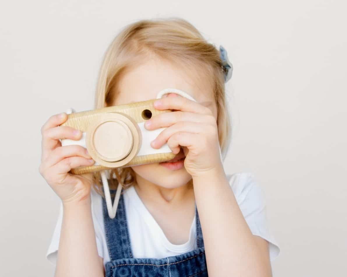 Girl holding wooden toy camera